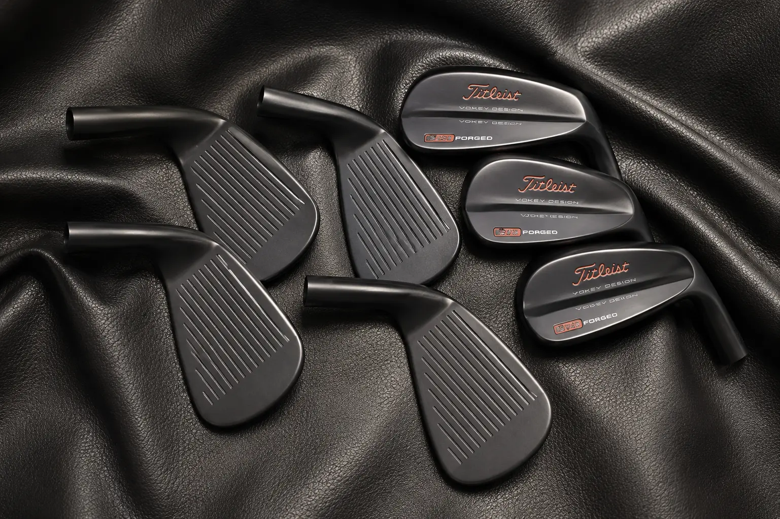 Blacked-out Cerakote coated golf club heads on leather